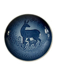 Blue ceramic plate with deer design on a textured beige surface