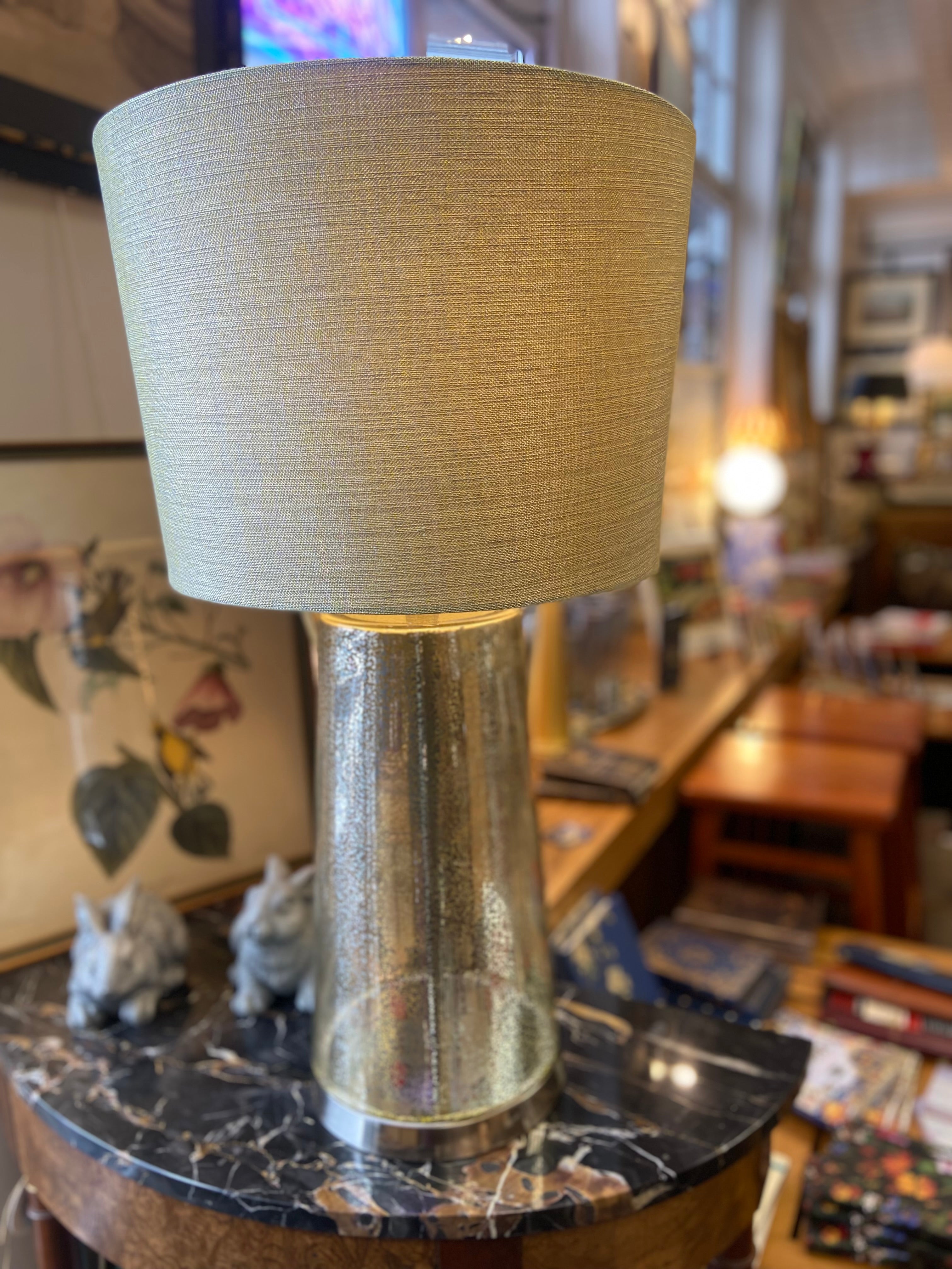 Table lamp with a textured beige shade and metallic base on a marble surface.